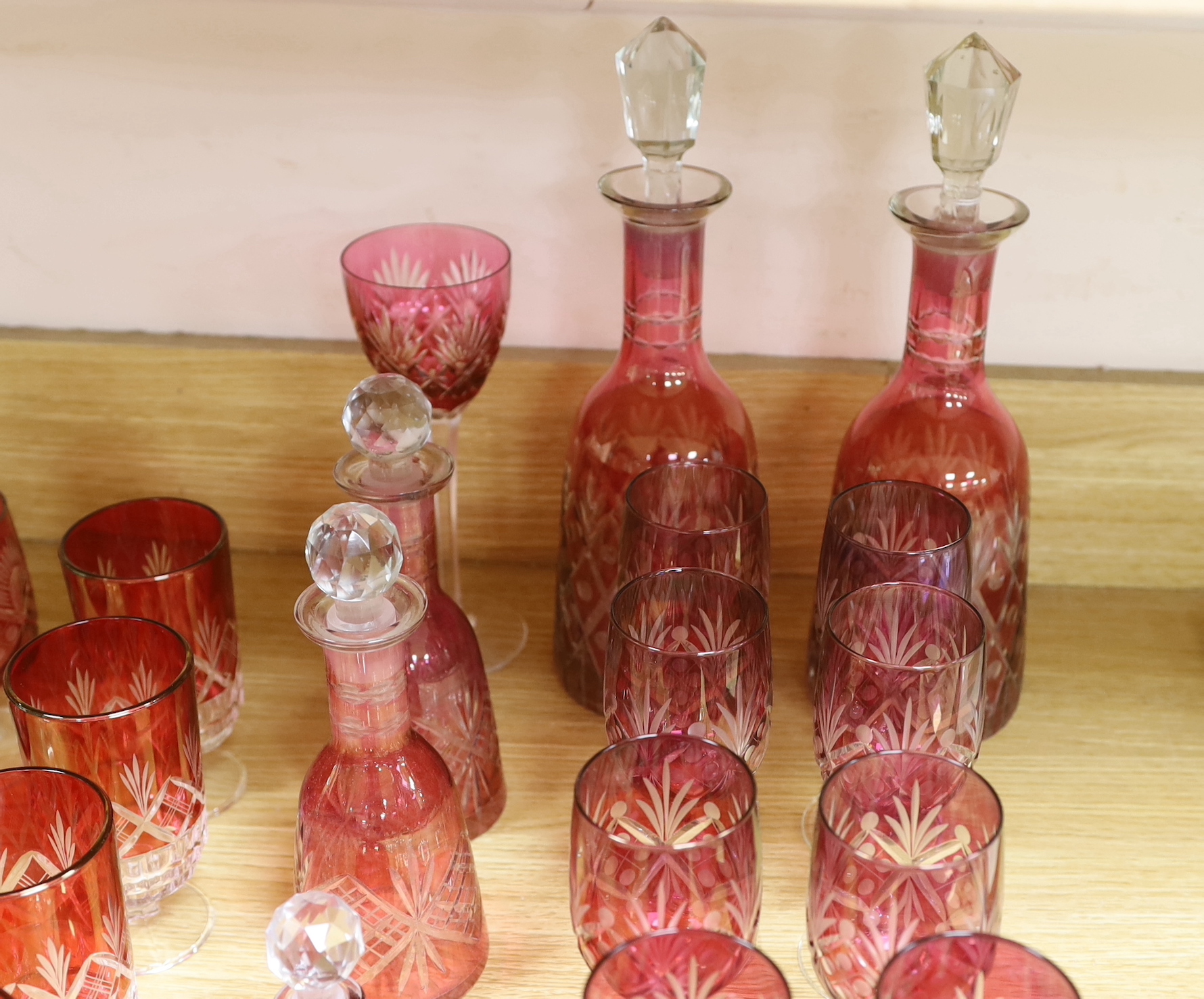 Cranberry glassware including a pair of cut glass decanters, together with a smaller pair and various suites of similar wine glasses, the largest 33cm high